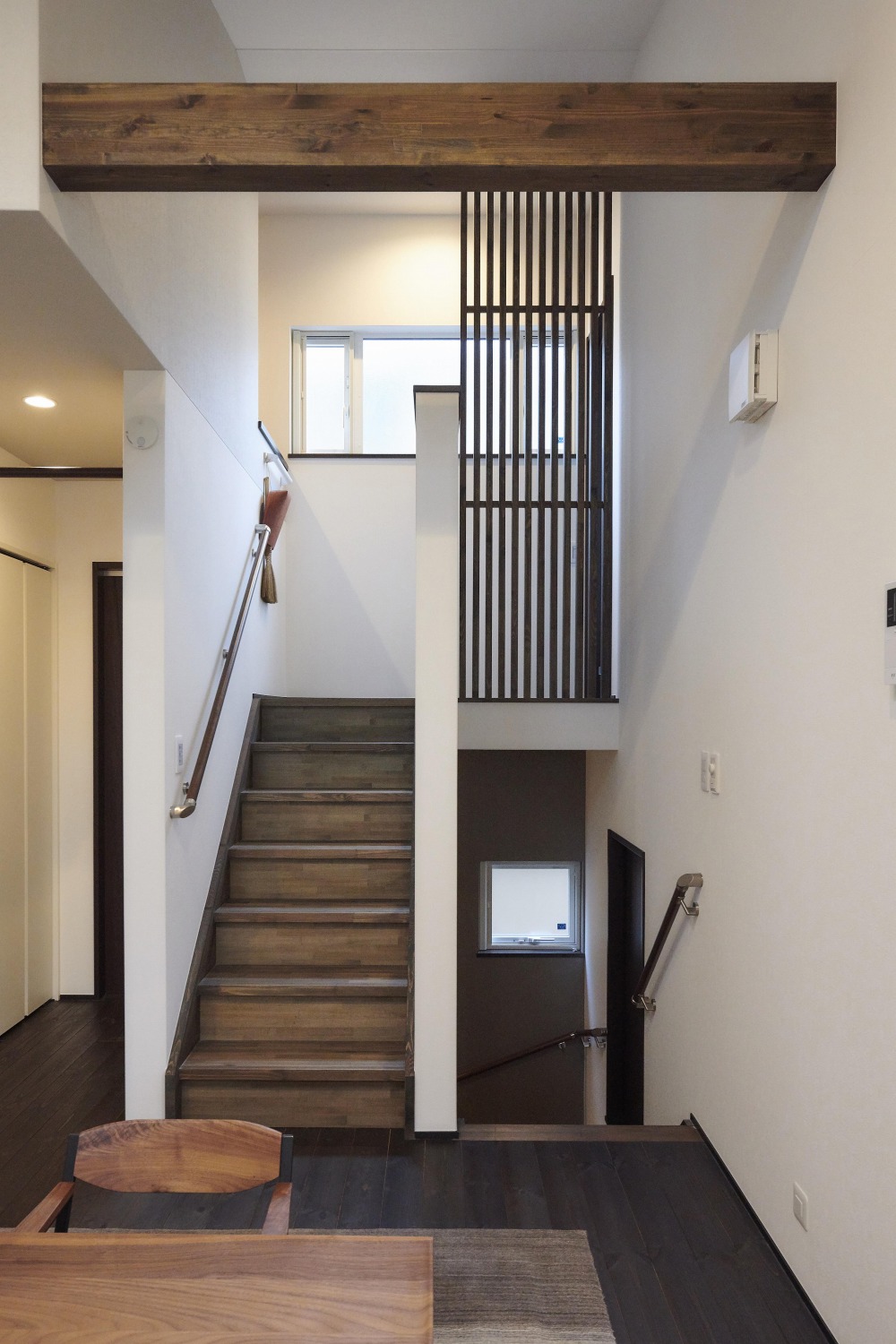 梁や格子などところどころに木質感を持たせることで空間の統一性のある2.5階へ続く階段の画像