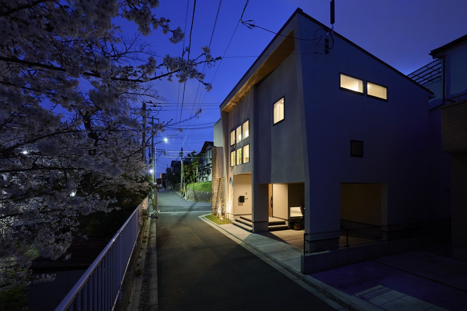 帰宅する家族をやさしく出迎え、夜桜を上品に照らす住まいの灯りの画像