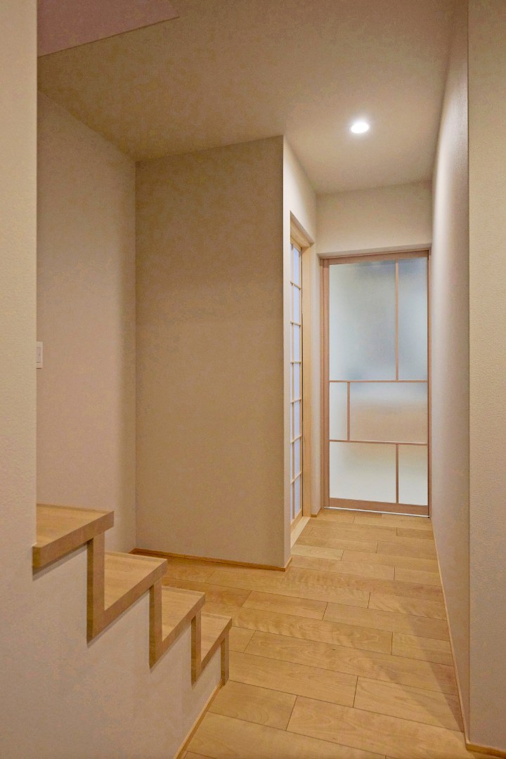 ひな壇階段の軽やかさと、障子越しの柔らかな光が調和する1階ホールの画像