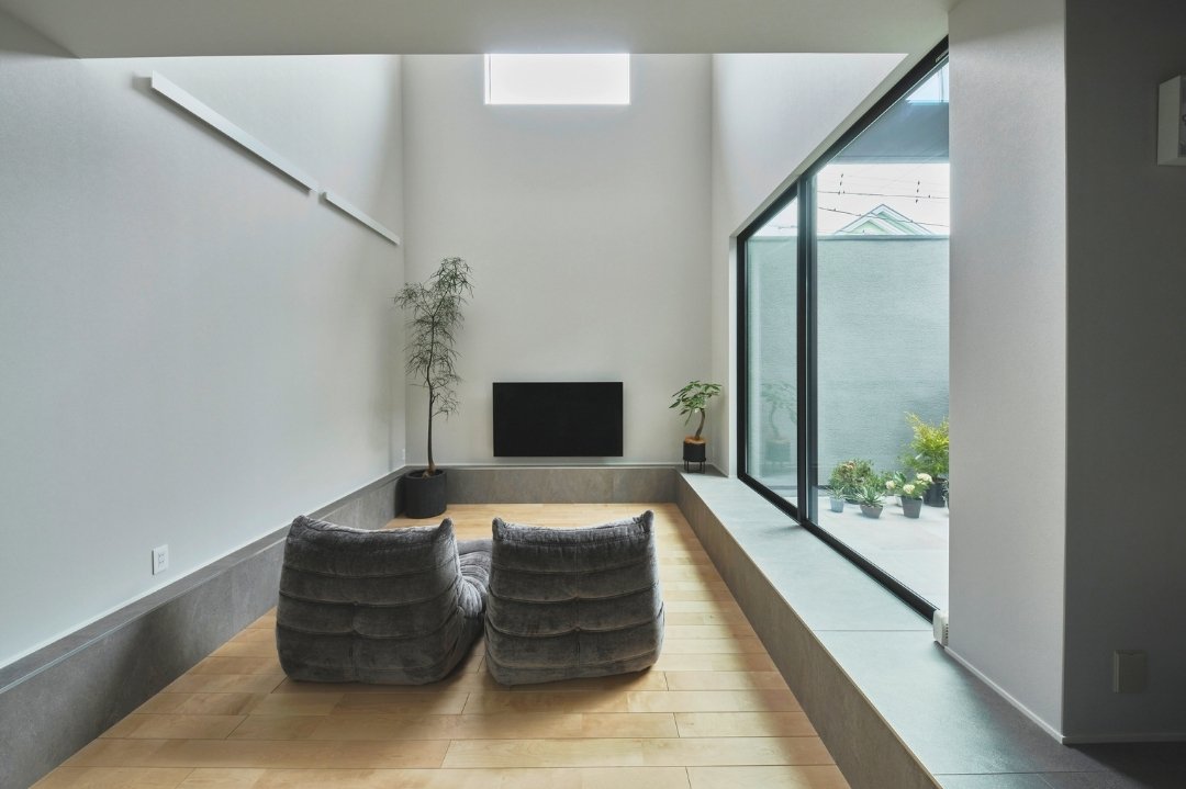 高窓から自然光が差し込む吹抜けのリビングの画像