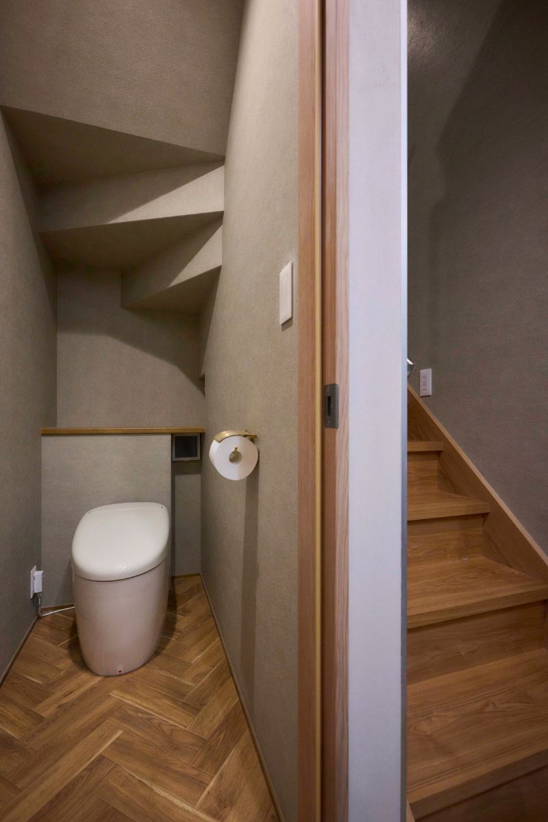 ヘリンボーン柄の床がおしゃれな、階段下を活用した1階トイレの画像