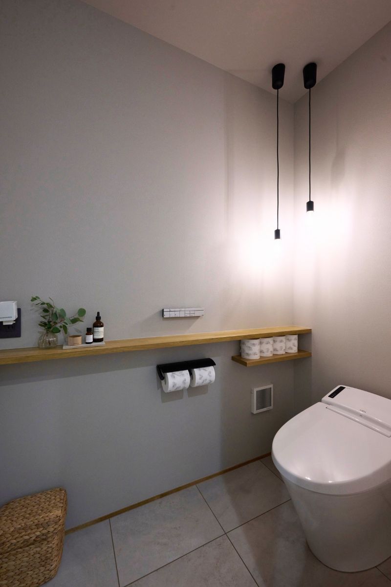 無機質な空間に温かみのある木目柄と可愛らしいニッチを組み合わせた1階トイレの画像
